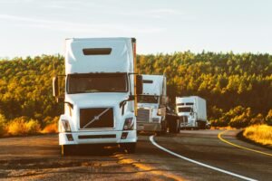 Transport de colis par camion Three semi trucks driving on a highway through a forested landscape in Arizona.